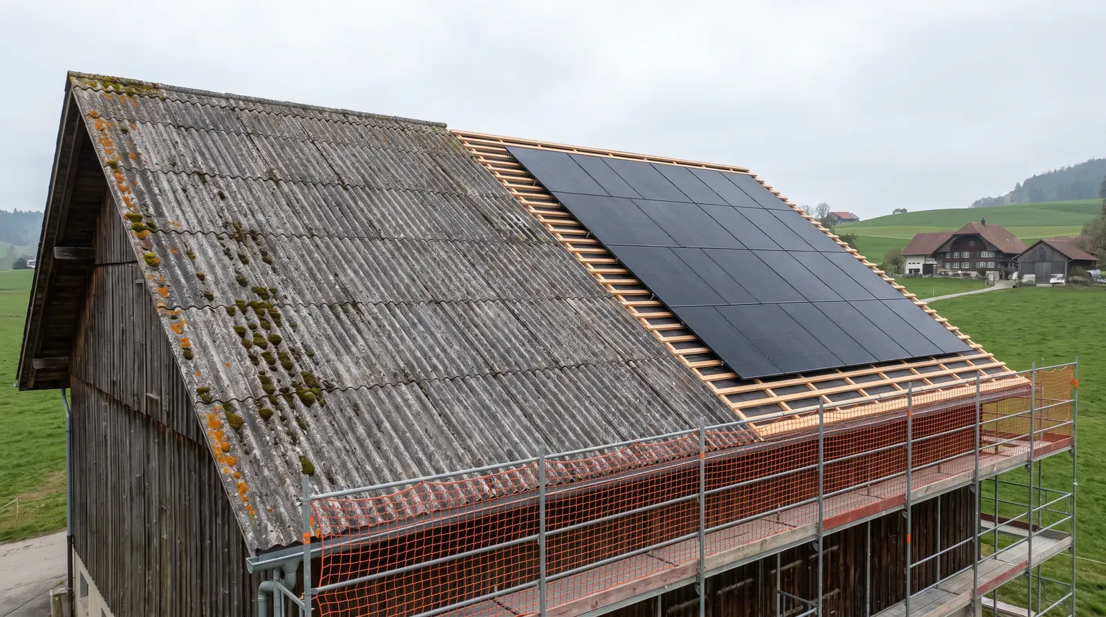 Scheunendach während der Sanierung: links alte graue Wellplatten mit Moos, rechts neue Dachlatten und schwarze Solarmodule, an der Traufe ein Gerüst mit Netz