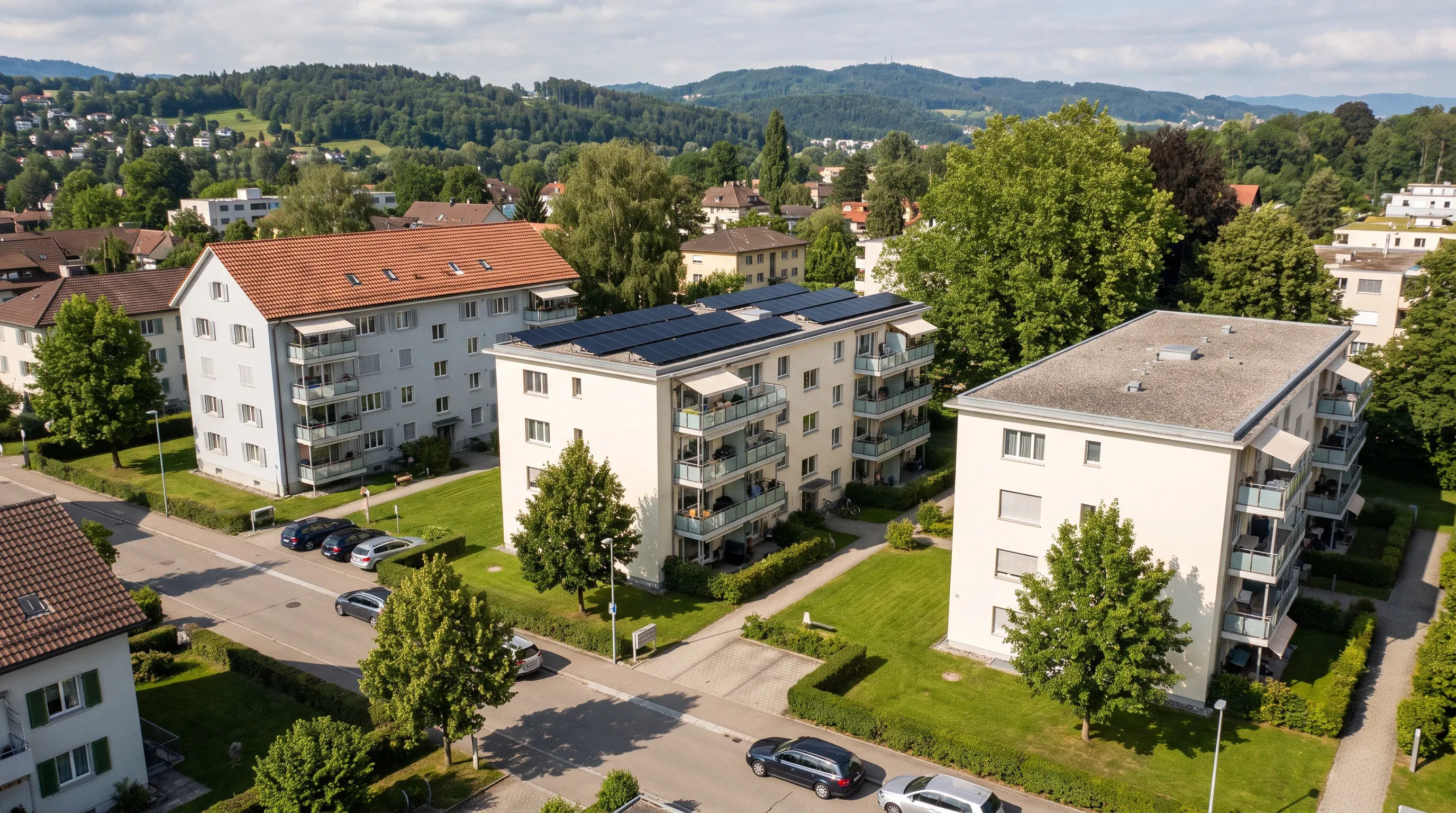 Wohnquartier mit drei Mehrfamilienhäusern, das mittlere hat eine Solaranlage auf dem Flachdach